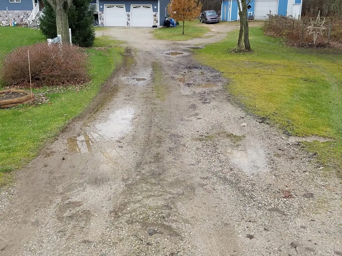 Gravel driveway with potholes and water damage